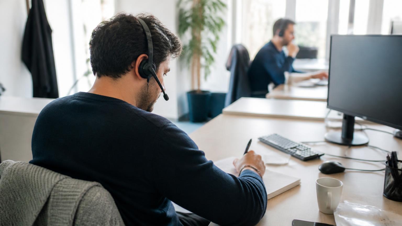 SDR au téléphone dans un bureau parisien, casque sur les oreilles, écran de prospection flouté